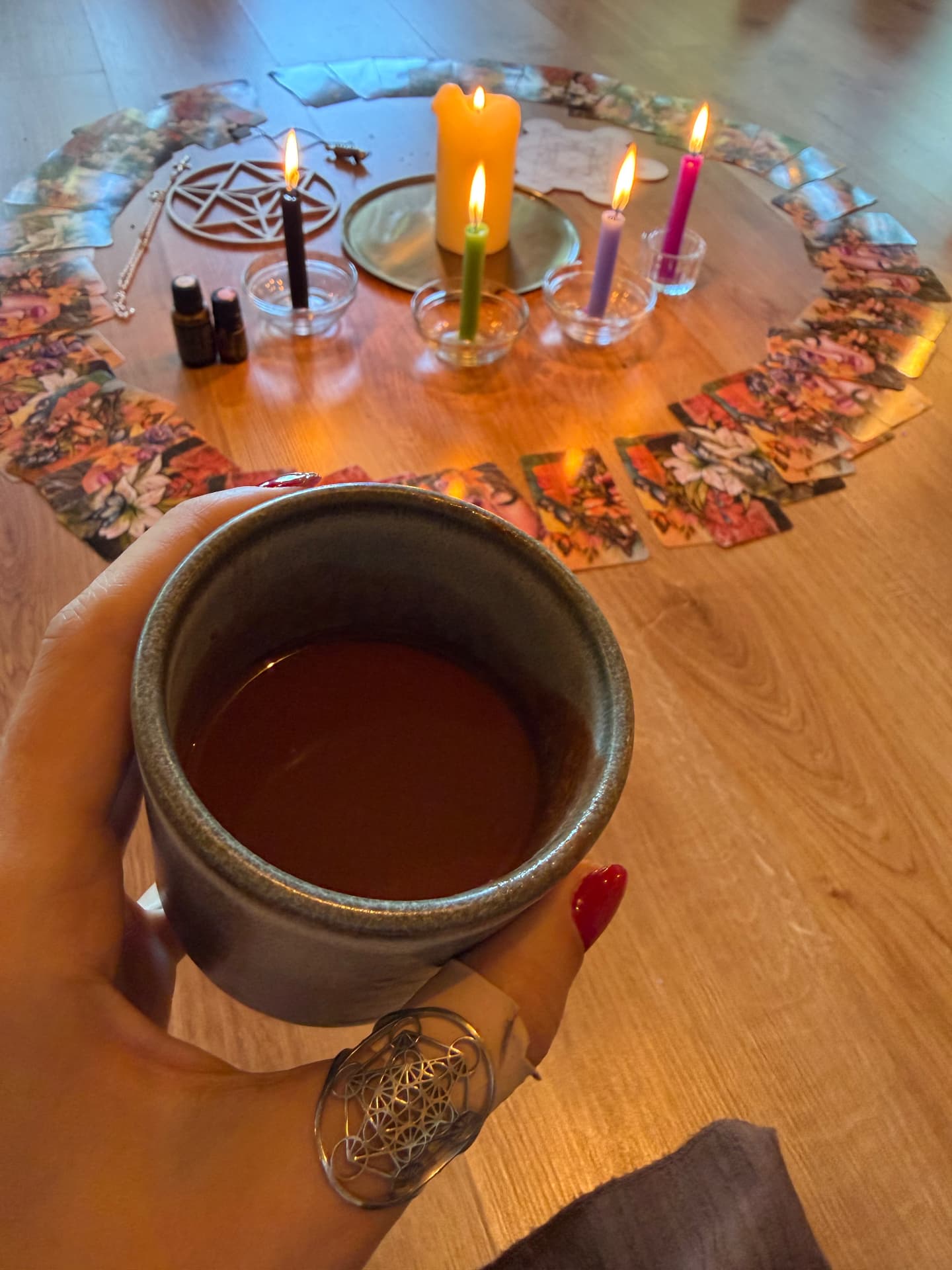 Chávena de cerâmica com chá de cacau sobre um círculo de cartas e velas