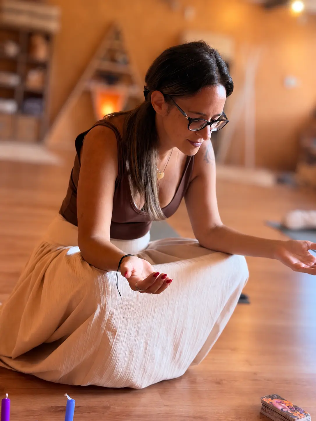 Paula, de óculos, sentada no chão do seu espaço com as cartas de orientação